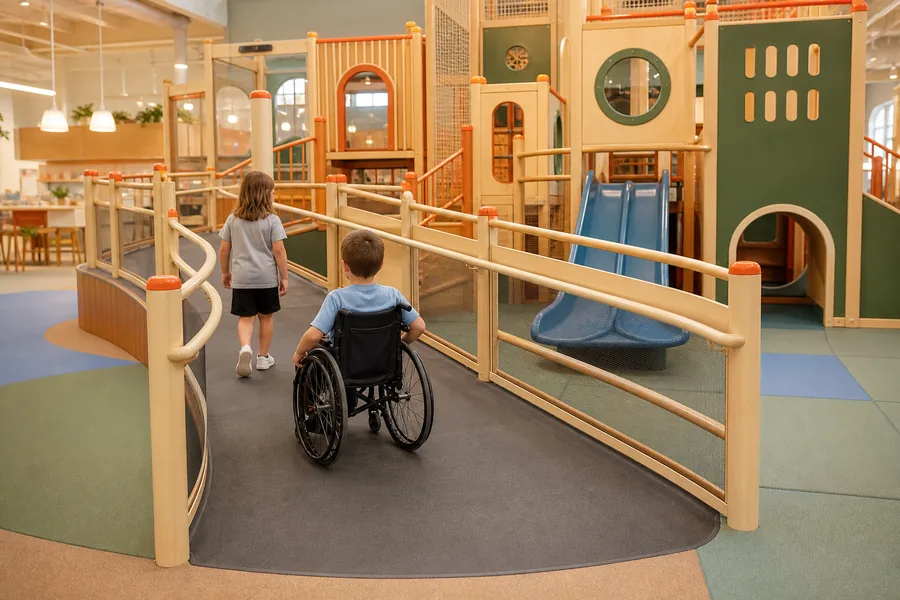 Sistema de rampas para un parque infantil cubierto, accesible para sillas de ruedas, que conduce a una estructura de juegos de varios niveles