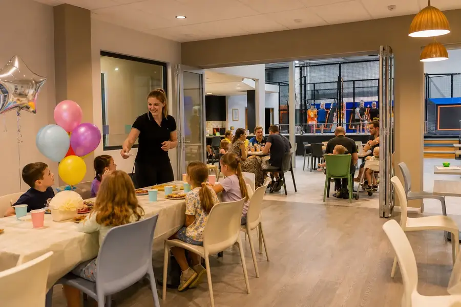 Birthday party room connected to cafe seating and a separated trampoline court in a family entertainment center