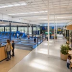 Commercial trampoline park with a main court, toddler zone, reception, party rooms, and cafe seating