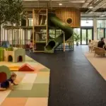 Commercial indoor playground with foam padding, rubber flooring, and carpeted lounge zones