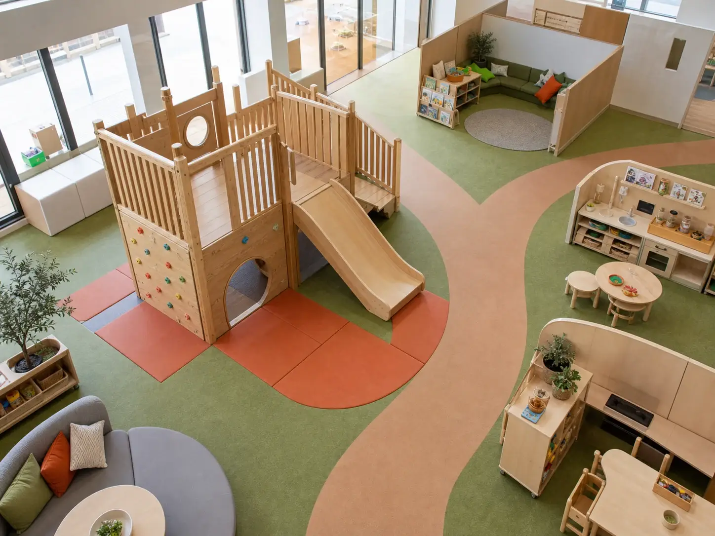 Daycare indoor playroom layout with a wood playground climber, clear circulation paths, soft landing zones, and nearby quiet play areas