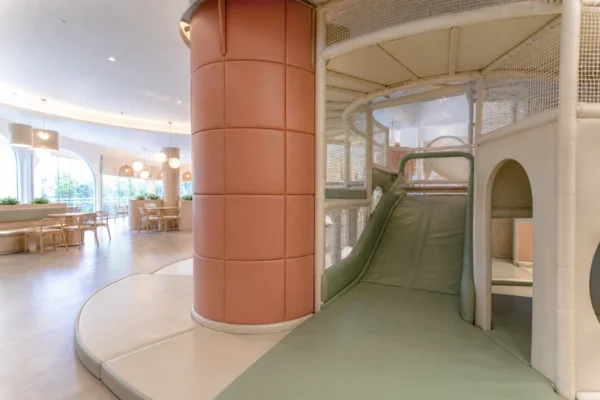Commercial soft play structure with a PVC-covered padded column, slide, and cleanable landing pads.